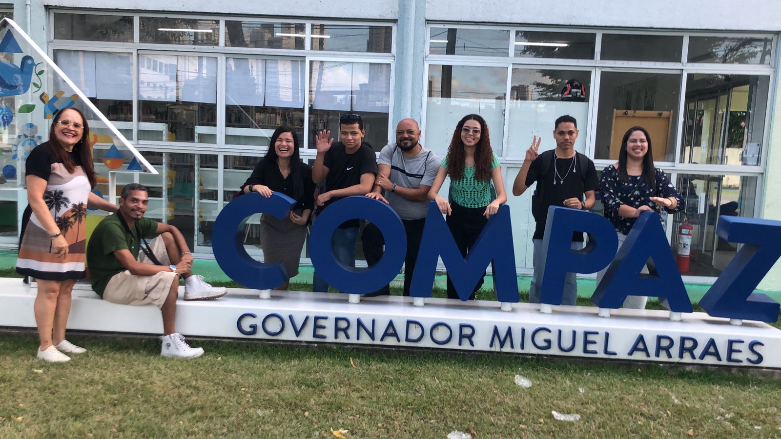 Equipe do projeto posando para foto ao redor do letreiro azul do COMPAZ Miguel Arraes